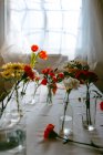Окуляри зі свіжих тюльпанів і гвоздик у воді розміщені на столі для виготовлення букетів — стокове фото