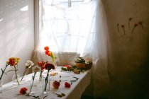 Стаканы свежих тюльпанов и гвоздик в воде, поставленные на стол для приготовления букетов — стоковое фото