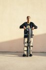 Junger ethnischer Hipster männlicher Athlet in cooler Kleidung sitzt auf einem BMX-Rad, während er an einem sonnigen Tag in die Kamera schaut — Stockfoto