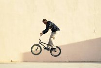 Молодой афроамериканец выполнял трюк на пробном велосипеде в скейт-парке города — стоковое фото
