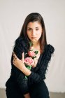 Young sensual female in black clothes with blossoming flower looking at camera — Stock Photo