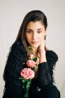Junge sinnliche Frau in schwarzen Kleidern mit blühender Blume blickt in die Kamera — Stockfoto