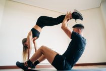 Ganzkörper-Seitenansicht eines entschlossenen Mannes und einer entschlossenen Frau in sportlicher Kleidung, die schwierige Yogapositionen ausführen, während sie zu Hause üben — Stockfoto