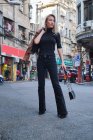 Belle jeune fille blonde posant autour du centre-ville chinois avec des vêtements noirs — Photo de stock