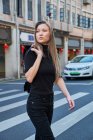 Schöne blonde junge Mädchen zu Fuß durch die chinesische Innenstadt und überqueren die Straße an der Kreuzung — Stockfoto