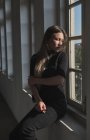 Portrait of beautiful young girl with long blond hair, she is near to the window and the sunlight is lighting her face. — Stock Photo