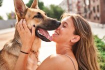 Positivo proprietário do sexo feminino abraçando cão pastor alemão enquanto sentados juntos — Fotografia de Stock