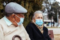 Вид збоку на літню пару, що носить маску для обличчя на вулиці, коли вони дивляться на зимовий день — стокове фото