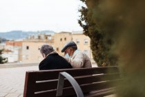 Back view of an unrecognizable elderly couple sitting on a park bench — Stock Photo