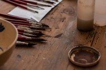 Dall'alto di varie spazzole vicino a piatto di ceramica dipinto su tavolo di legno in officina — Foto stock