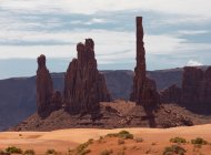 Incredibile scenario di alti monumenti rocciosi situati nel deserto soleggiato terreno sabbioso contro cielo nuvoloso nel parco nazionale degli Stati Uniti — Foto stock