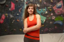 Charming strong woman in sportswear with crossed arms standing near climbing wall and looking at camera — Stock Photo