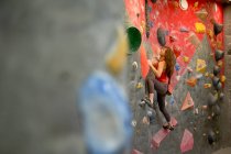 Side view of strong female athlete in sportswear clambering wall in modern bouldering center — Stock Photo