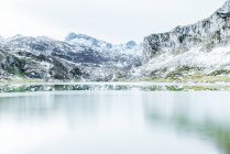 Дивовижні пейзажі суворого гірського хребта зі схилами в снігу і холодним замерзлим озером на дні чистого зимового дня — стокове фото