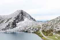Spektakuläre Aussicht auf felsige, schneebedeckte Bergkette in der Nähe des ruhigen Sees und des weitläufigen, grasbewachsenen Tals in ruhiger Natur in Asturien — Stockfoto