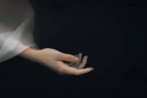 Da sopra raccolto sottile mano femminile in manica traslucida bianco bagnato galleggiante in acqua di lago scuro — Foto stock