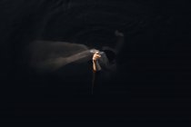Вид зверху на невизначену жінку-мандрівника, що покриває обличчя текстилем, стоячи з піднятими руками у воді в сутінках — стокове фото