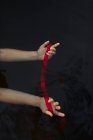 Vue du dessus d'une voyageuse anonyme avec les bras atteints montrant un bandeau rouge dans l'eau sur fond noir — Photo de stock