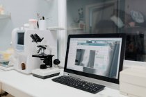 From above of microscope near computer with open program on screen in vet laboratory — Stock Photo