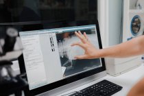 Crop anonymous veterinarian showing X ray image on computer screen while working in lab — Stock Photo