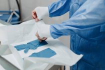 Schnittansicht eines anonymen jungen Tierarztes in steriler Uniform, der elastische Handschuhe anzieht, während er sich auf die Operation im Operationssaal vorbereitet — Stockfoto