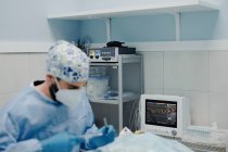 Konzentrierter männlicher Tierarzt in Uniform und Atemmaske mit medizinischen Instrumenten während der Operation im Krankenhaus — Stockfoto