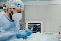 Konzentrierter männlicher Tierarzt in Uniform und Atemmaske mit medizinischen Instrumenten während der Operation im Krankenhaus — Stockfoto