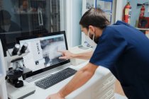 Anonymer Tierarzt zeigt Röntgenbild auf Computerbildschirm, während er im Labor arbeitet — Stockfoto