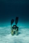 Тонка жінка в купальнику і лапах плаває під водою в бірюзовому морі — стокове фото
