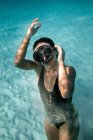 From above of slim female in swimsuit and flippers swimming underwater in turquoise sea — Stock Photo