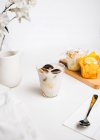 Composición de bombas de chocolate dulce que se derriten en un vaso de leche caliente fresca colocado en la mesa cerca de deliciosos cupcakes y jarra de leche - foto de stock