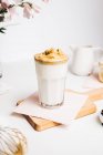 Teaspoon with sweet whipped foam above fresh yummy latte served on wooden cutting board in modern light kitchen — Stock Photo