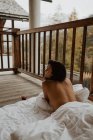 Voltar vista atraente topless feminino relaxante em cobertor macio com xícara de bebida quente no alpendre da casa de campo de madeira no dia de outono — Fotografia de Stock