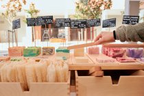 Анонімний покупець врожаю збирає мило з натуральних інгредієнтів під час покупки в магазині з екологічно чистими продуктами — стокове фото