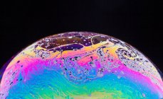 Vista panoramica di primo piano bolla texture sfondo che rappresenta colorato pianeta con linee ondulate su superficie rotonda sagomata su sfondo nero — Foto stock