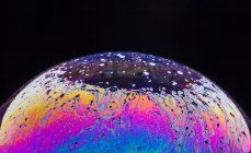 Panorama-Ansicht der Nahaufnahme Blase texturierten Hintergrund darstellt bunte Planeten mit wellenförmigen Linien auf runden geformten Oberfläche auf schwarzem Hintergrund — Stockfoto