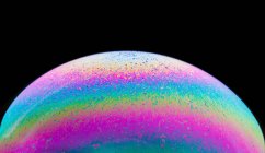 Vue panoramique de gros plan bulle texturé toile de fond représentant la planète colorée avec des lignes ondulées sur la surface en forme ronde sur fond noir — Photo de stock