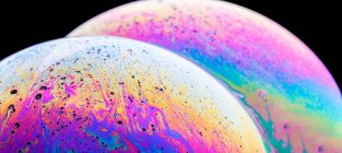 Panoramic view of closeup bubble textured backdrop representing colorful planets with wavy lines on round shaped surface on black background — Stock Photo