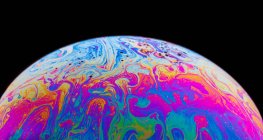 Vista panoramica di primo piano bolla texture sfondo che rappresenta colorato pianeta con linee ondulate su superficie rotonda sagomata su sfondo nero — Foto stock