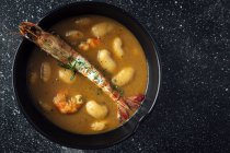 From above of appetizing cream soup with white beans and langoustines served in bowl and placed on marble tabletop in kitchen — Stock Photo