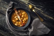 Зверху апетитний вершковий суп з білою квасолею і лангоустинами подається в мисці і розміщується на дерев'яній стільниці біля серветки на кухні — стокове фото