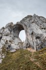 Viajero lejano de pie en un gran agujero de formación rocosa áspera en Asturias España en un día nublado - foto de stock