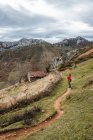 Vista lateral viajante sem rosto em pé no caminho rural na encosta gramínea em terreno montanhoso espaçoso no dia nublado em Astúrias Espanha — Fotografia de Stock