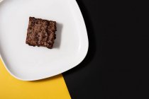 Кусок свежего брауни на черно-желтом фоне — стоковое фото