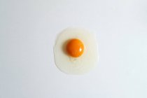Вид зверху на свіже сире куряче яйце, розміщене на білому тлі в яскравій студії — стокове фото