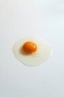 Вид зверху на свіже сире куряче яйце, розміщене на білому тлі в яскравій студії — стокове фото