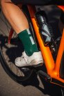Урожай неузнаваемый велогонщик в шортах и кроссовках на современном велосипеде на солнечной летней улице — стоковое фото