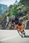 Corpo completo di giovane sportivo in activewear e casco in bicicletta su strada asfaltata nella giornata di sole — Foto stock