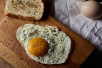 From above of appetizing fried eggs served with fresh bread on wooden chopping board — Stock Photo