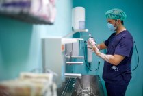 Seitenansicht eines anonymen jungen Arztes in medizinischer Uniform und Maske, der sich vor der Operation im Operationssaal die Hände mit Seife wäscht — Stockfoto